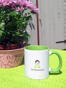 Gartenmoni Tasse für Kaffee und Tee auf dem Tisch neben Blumen